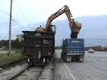 Cat 319DL unloading rock from a train