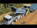 Construction machinery actively paving a road. A dump truck is unloading gravel into a gravel paver