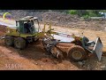 A yellow construction grader machine is leveling and pushing red soil at a construction site